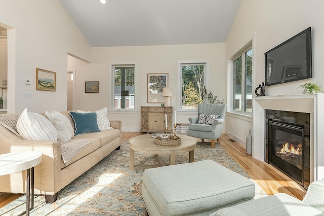 37 Cascade Cir Unit 26, Kennebunk, ME 04043 - living area featuring high vaulted ceiling, baseboards, a glass covered fireplace, and light wood-style floors