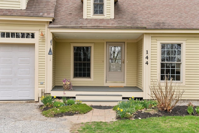 entrance to property with roof with shingles, covered porch, and a garage