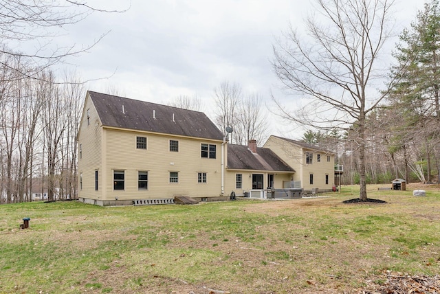 rear view of house with a lawn, a chimney, and a shingled roof