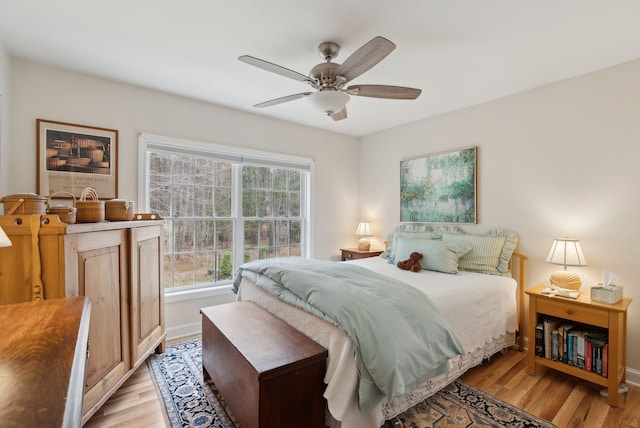 bedroom featuring baseboards, a ceiling fan, and light wood-style flooring