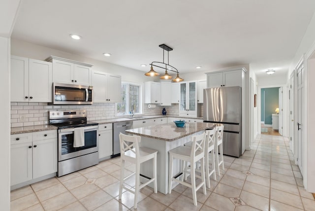 kitchen featuring decorative backsplash, a kitchen breakfast bar, appliances with stainless steel finishes, a sink, and light stone counters