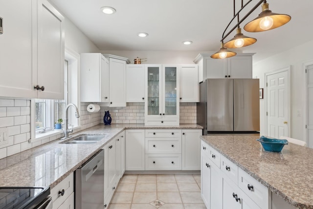 kitchen with a sink, appliances with stainless steel finishes, white cabinets, and tasteful backsplash