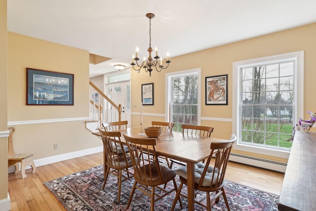 dining room with baseboard heating, stairway, baseboards, wood-type flooring, and a chandelier