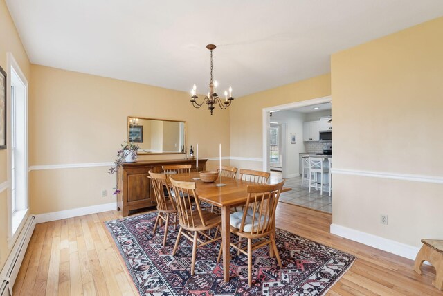dining room with baseboards, a baseboard radiator, light wood-type flooring, and a chandelier