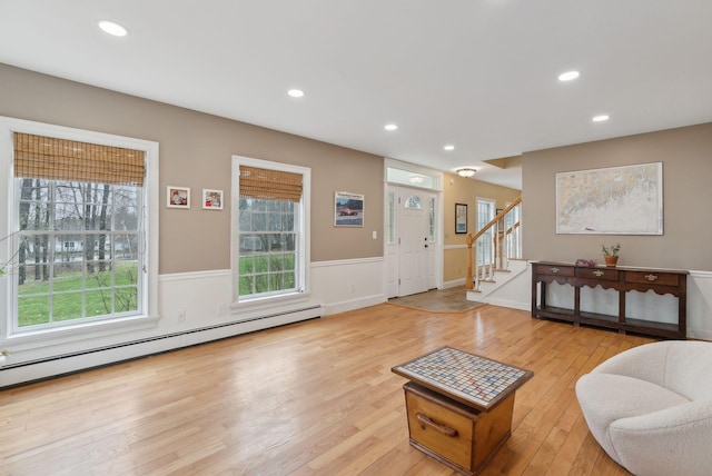 living room with baseboard heating, a wainscoted wall, stairs, recessed lighting, and light wood-type flooring