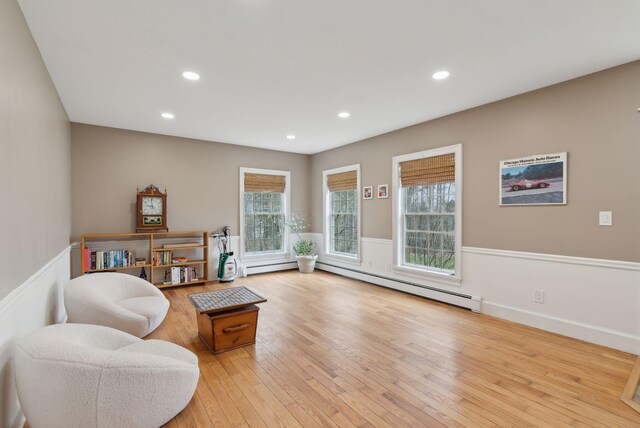 living area with light wood-style floors, wainscoting, a baseboard heating unit, and recessed lighting