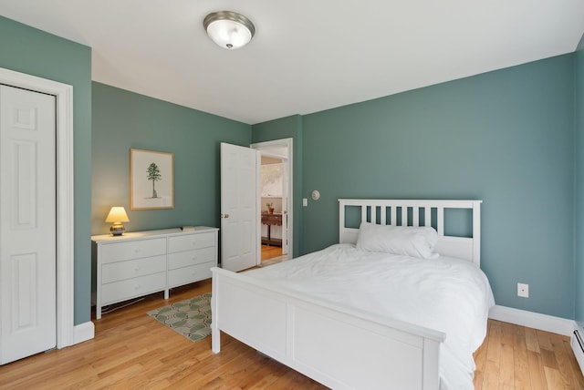 bedroom featuring baseboards, light wood-style flooring, and baseboard heating