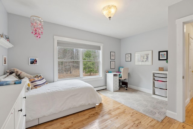 bedroom featuring baseboards, light wood finished floors, and a baseboard heating unit