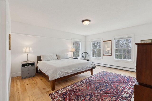 bedroom featuring baseboards, a baseboard radiator, and light wood finished floors