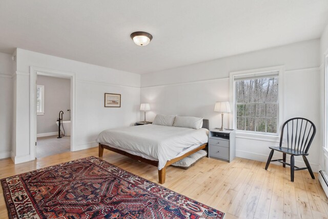 bedroom featuring light wood-type flooring, baseboards, and baseboard heating