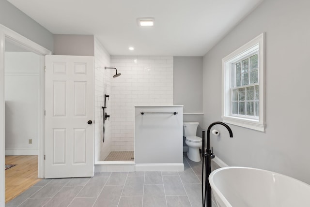 bathroom featuring a freestanding tub, tile patterned floors, a tile shower, and toilet