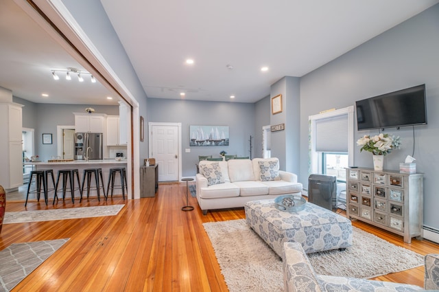 living area with recessed lighting, baseboard heating, and light wood-type flooring