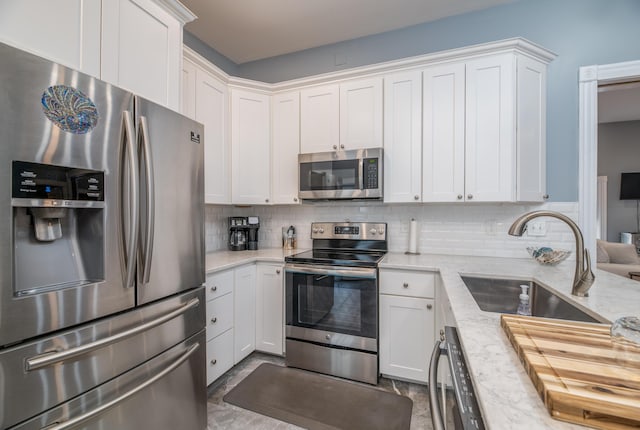 kitchen with a sink, white cabinets, appliances with stainless steel finishes, and tasteful backsplash