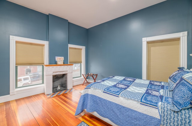 bedroom featuring wood finished floors and a brick fireplace