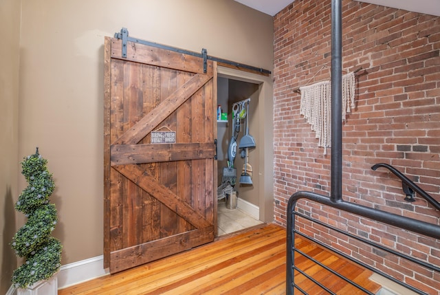 interior space with a barn door, brick wall, and wood-type flooring