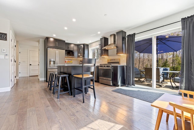 64 Rolling Brook Rd, Raymond, ME 04071 - kitchen featuring light wood-type flooring, a kitchen bar, appliances with stainless steel finishes, and wall chimney range hood