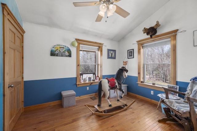 living area with hardwood / wood-style flooring, a wealth of natural light, and vaulted ceiling