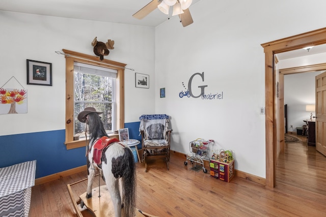 sitting room with wood finished floors, a ceiling fan, and baseboards