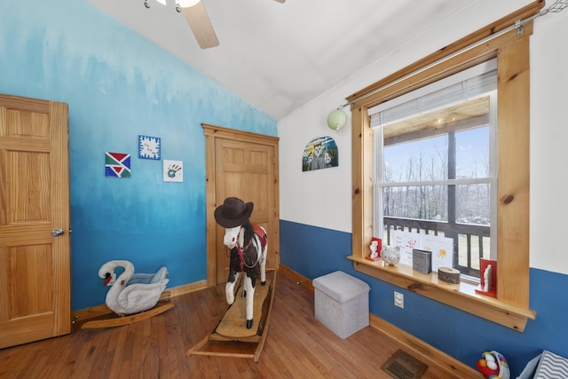 interior space with wood finished floors, vaulted ceiling, ceiling fan, baseboards, and visible vents