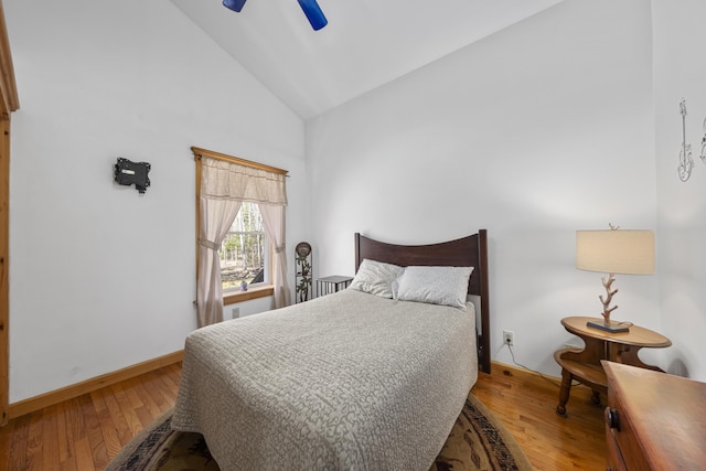 bedroom with wood finished floors, a ceiling fan, high vaulted ceiling, and baseboards