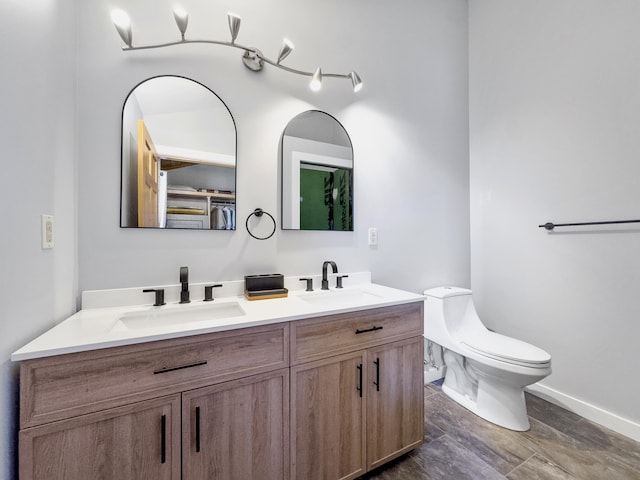 full bathroom featuring double vanity, toilet, baseboards, and a sink