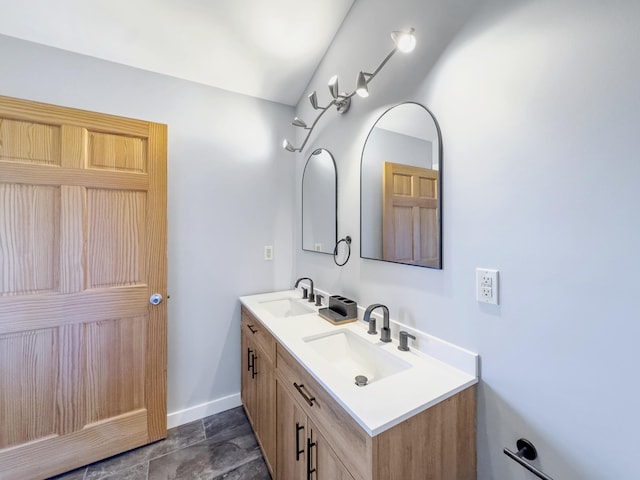 full bathroom with baseboards, double vanity, and a sink