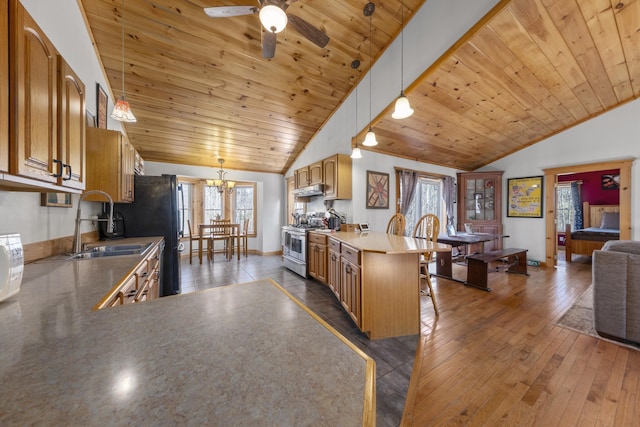 kitchen featuring wooden ceiling, a kitchen breakfast bar, vaulted ceiling, a peninsula, and stainless steel gas stove