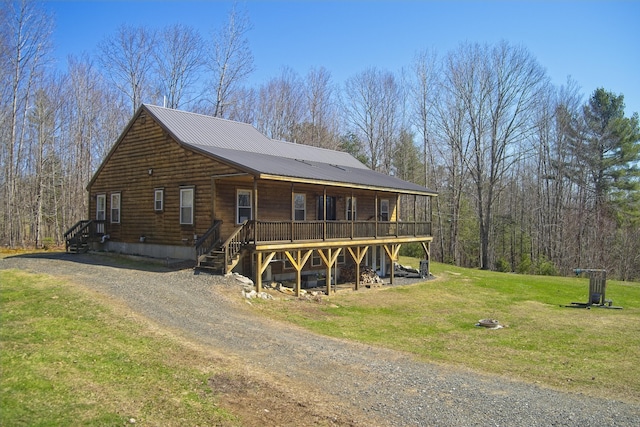 view of front facade featuring a deck, stairway, metal roof, dirt driveway, and a front yard