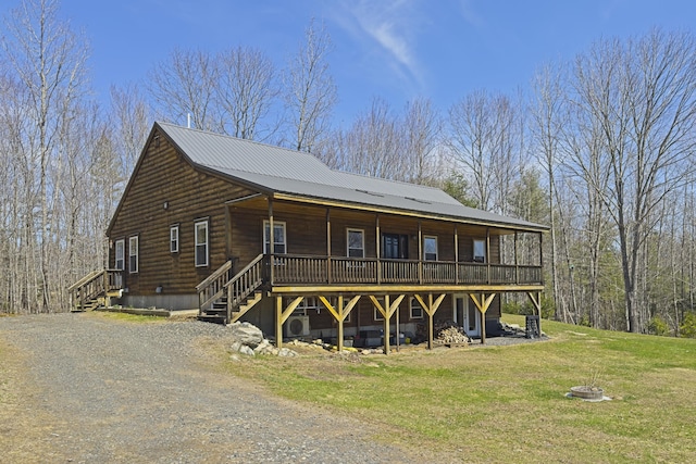 view of front of property with a deck, metal roof, and a front lawn