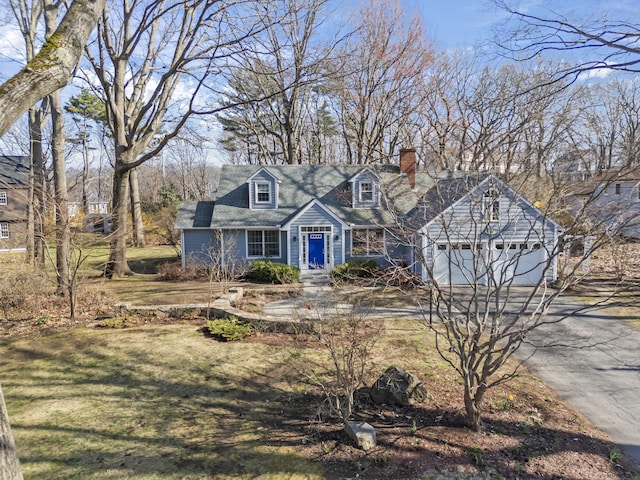 view of front of house with a front lawn, an attached garage, driveway, and a chimney