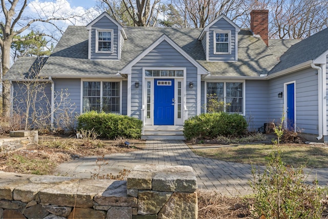 new england style home with a chimney and roof with shingles