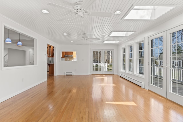 interior space with a baseboard radiator, a skylight, a baseboard heating unit, a healthy amount of sunlight, and french doors