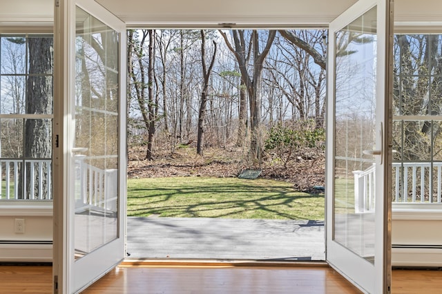 doorway to outside with baseboard heating and wood finished floors
