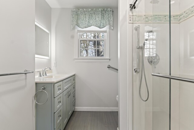 full bath with baseboards, vanity, toilet, and a stall shower