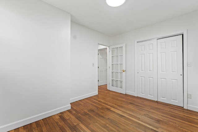 unfurnished bedroom featuring hardwood / wood-style floors, baseboards, and a closet