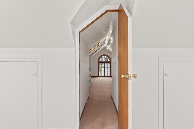 corridor featuring lofted ceiling and light carpet