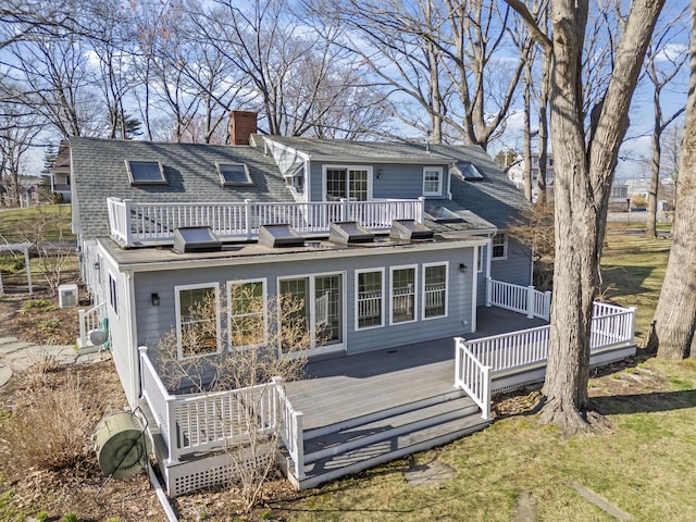 rear view of house featuring a shingled roof, a chimney, and a deck