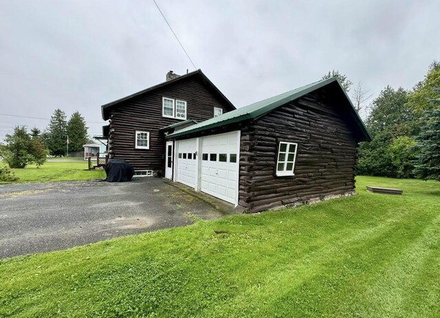 101 Mechanic St, Presque Isle, ME 04769 - view of home's exterior featuring a chimney, log siding, driveway, a lawn, and a garage