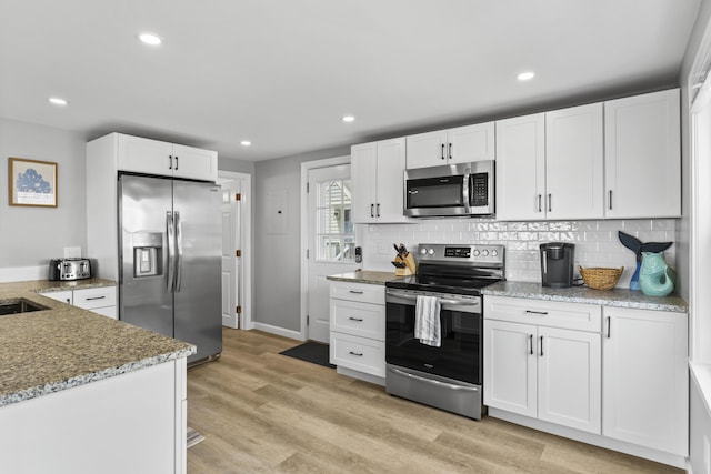175 Beach Ave Unit 2, Kennebunk, ME 04043 - kitchen featuring tasteful backsplash, baseboards, white cabinetry, light stone countertops, and appliances with stainless steel finishes
