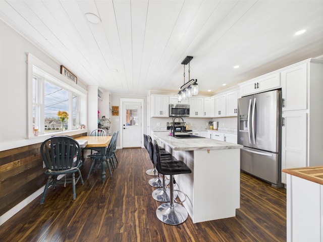 kitchen featuring appliances with stainless steel finishes, a breakfast bar, white cabinets, and dark wood-style floors