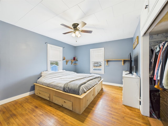 bedroom featuring baseboards, ceiling fan, a closet, and light wood-style flooring