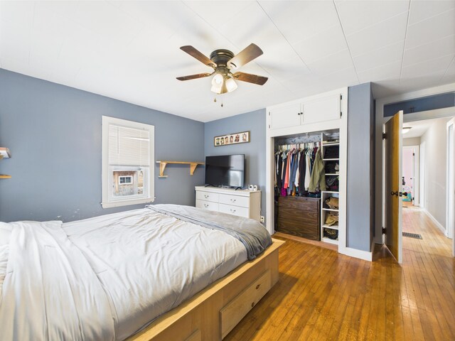 bedroom with ceiling fan, hardwood / wood-style flooring, visible vents, and a closet