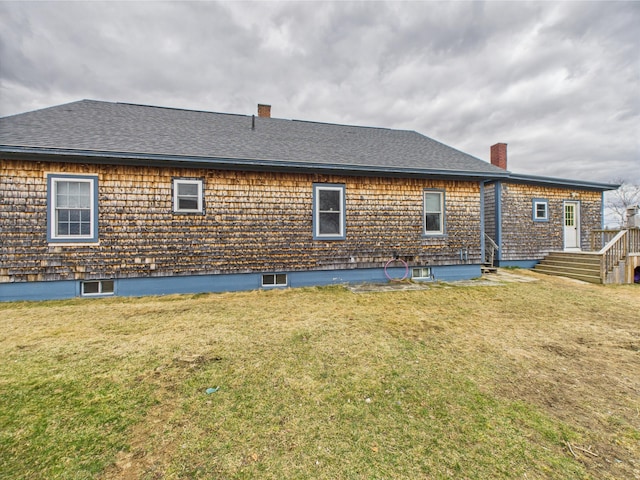rear view of property with a lawn, a chimney, and a shingled roof