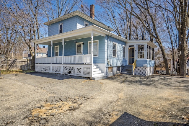 view of front facade with a chimney, fence, and a porch