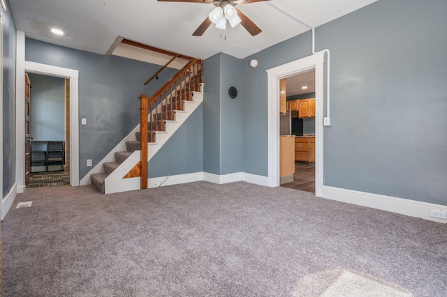 unfurnished living room with baseboards, carpet, stairs, and ceiling fan