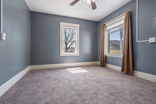 carpeted spare room featuring baseboards and ceiling fan