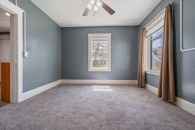 spare room with carpet floors, a ceiling fan, and baseboards
