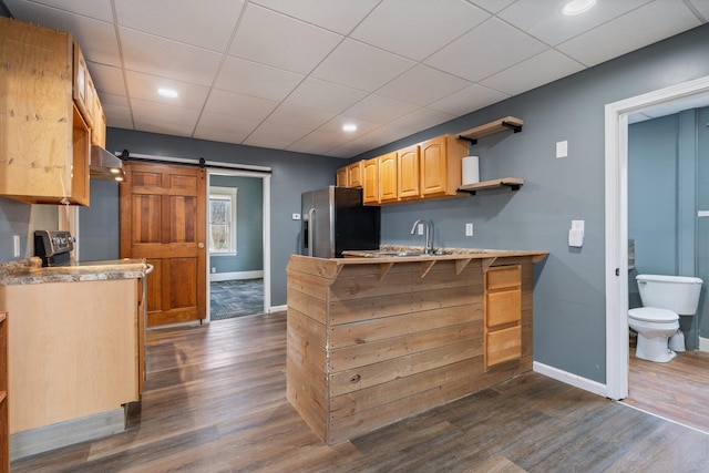 kitchen featuring dark wood-style flooring, a peninsula, baseboards, and stainless steel fridge with ice dispenser