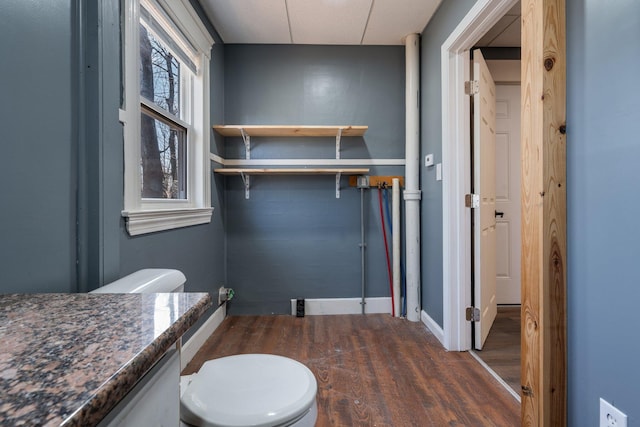 bathroom with baseboards, wood finished floors, toilet, and vanity