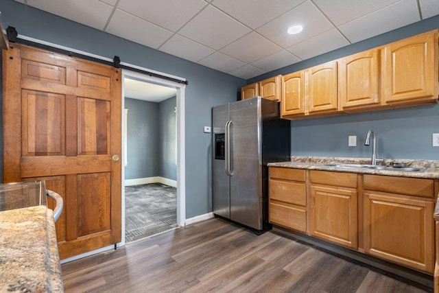 kitchen featuring a barn door, a sink, stainless steel fridge with ice dispenser, dark wood-style floors, and a paneled ceiling